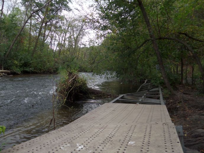 A broken pathway next to a stream.