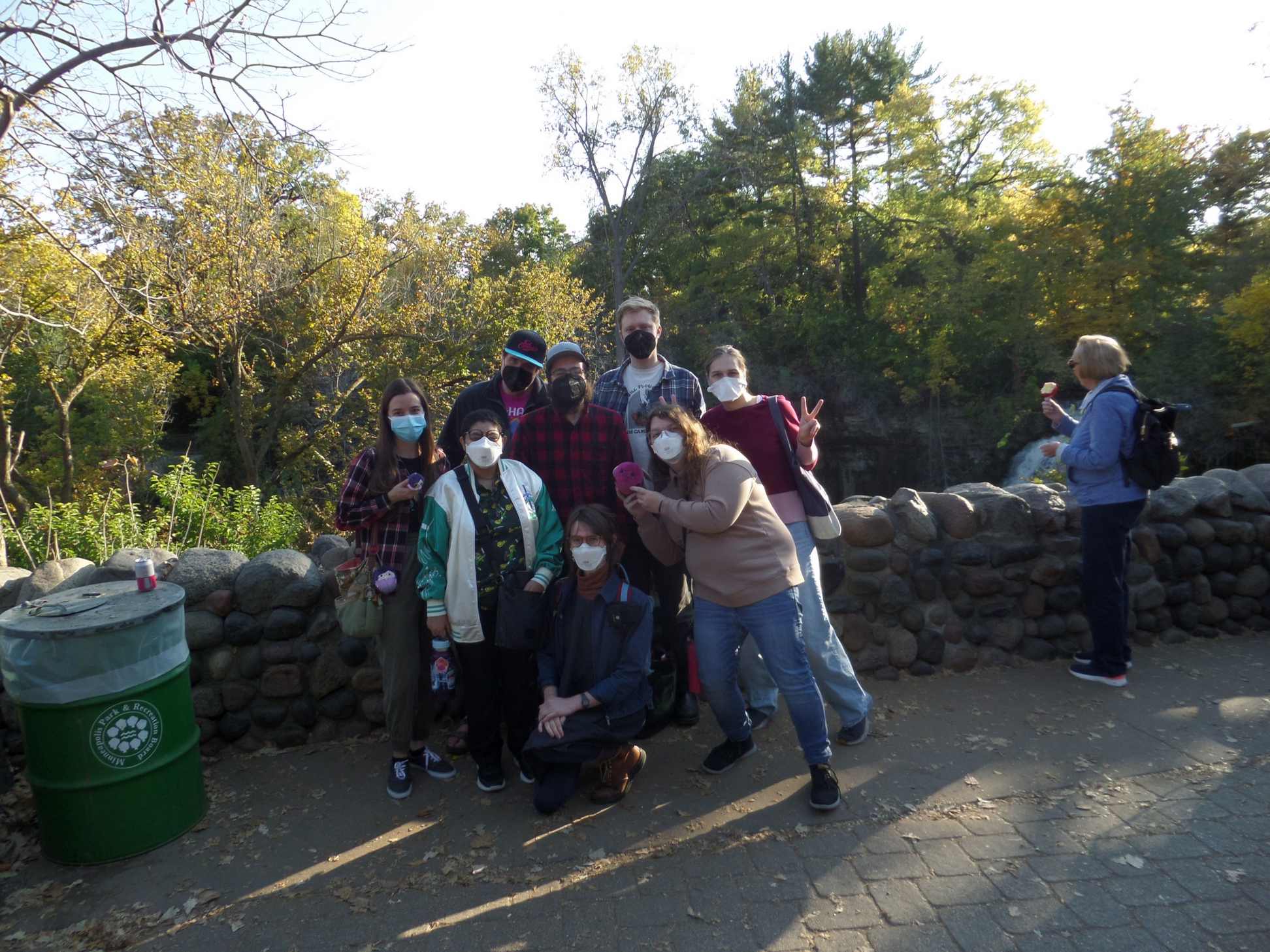 A group of masked nerds posing together in front of a low stone wall