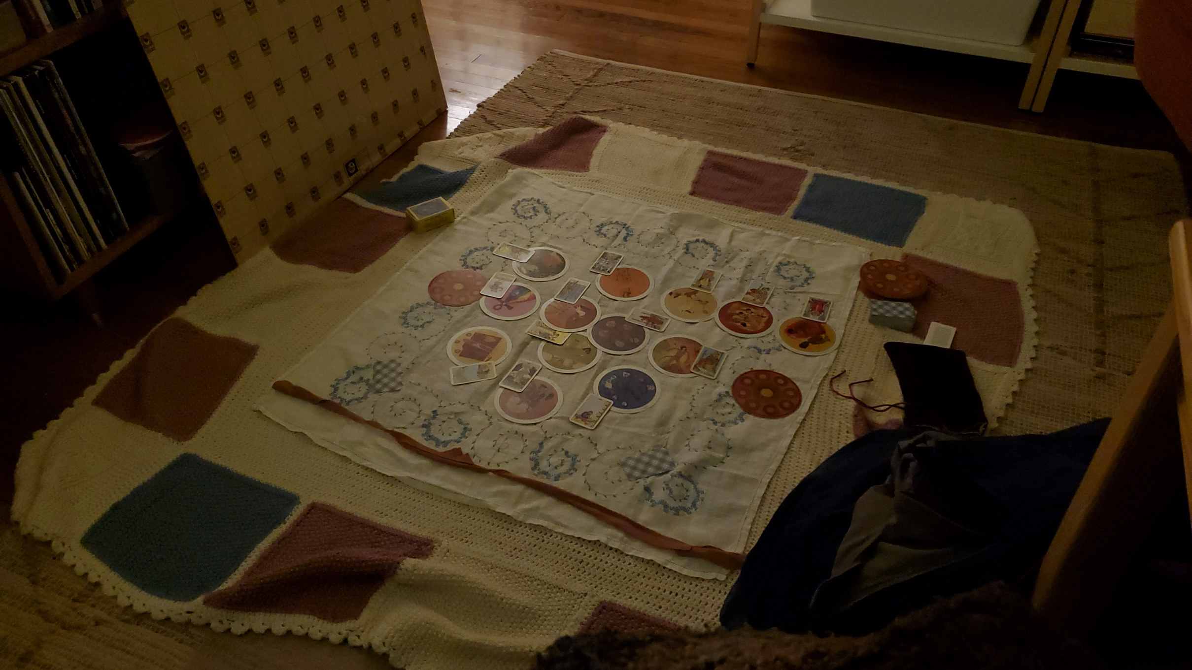 a wider shot of the blue, pink, and white blanket with the tarot spread on it. It's just on a rug on the floor.