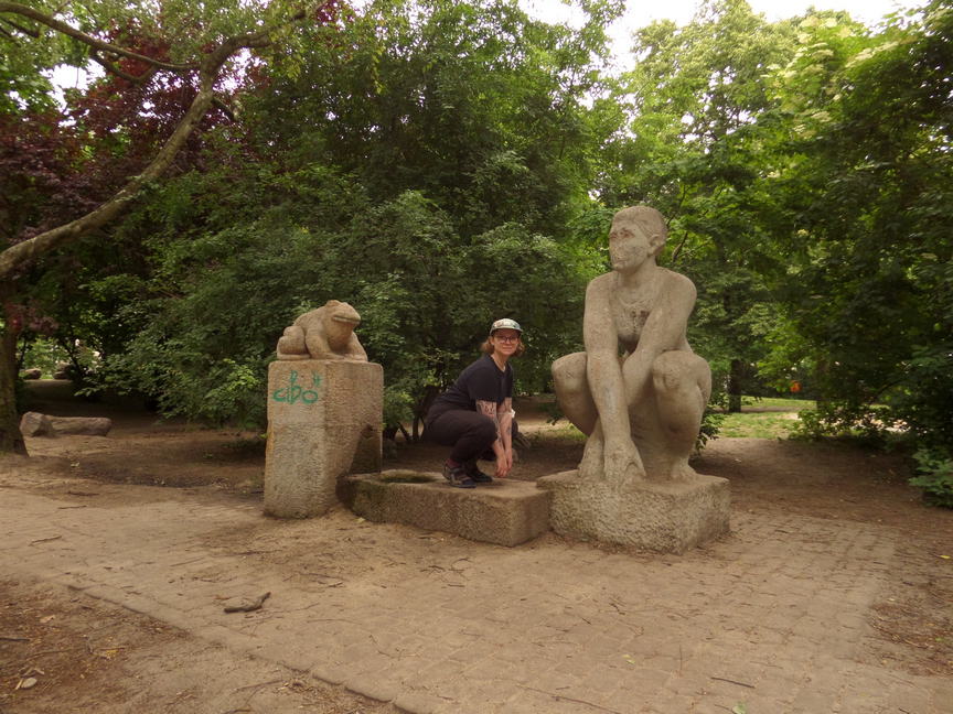 olivia perched frog pose between a frog statue and a statue of a woman crouched like a frog