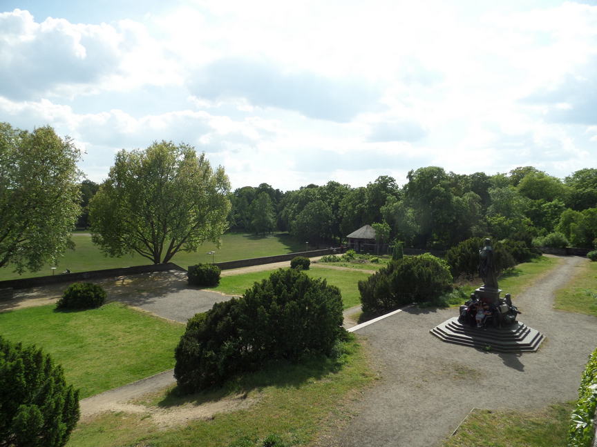 view from above of a tiered green park. teens are chilling on a statue.