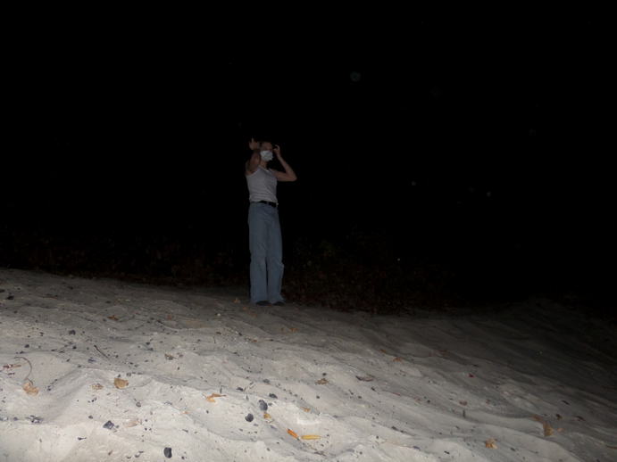 flash photo of a girl fixing her bangs on a hill of white sand.