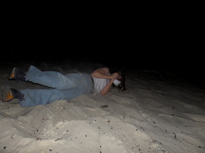 flash photo of a girl rolling down a hill of white sand.