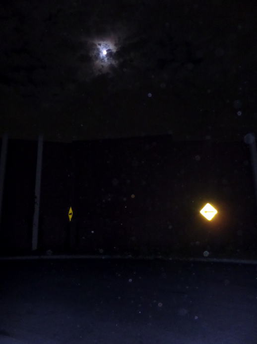 flash photo reflecting two road signs with the full moon overhead.