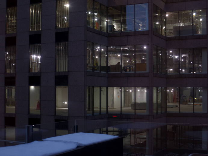 looking from one tall building into another one, empty and unfinished with the lights