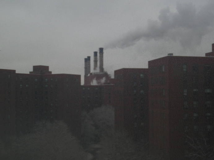 powerplant with smokestacks protruding above a line of buildlings in the foreground.