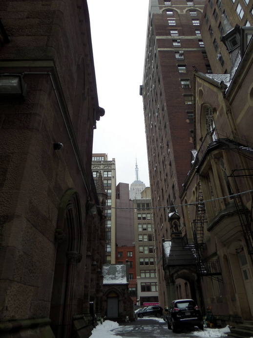 alleyway with a church on the left and a highrise on the righ