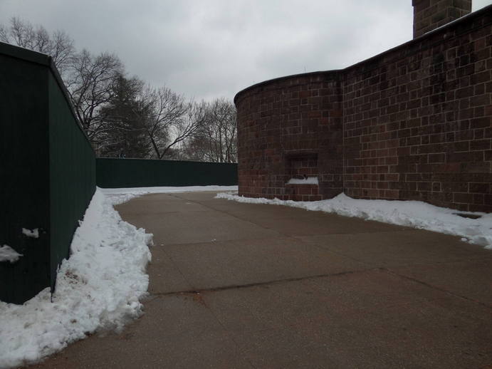 empty snowy concrete path around a brick wall