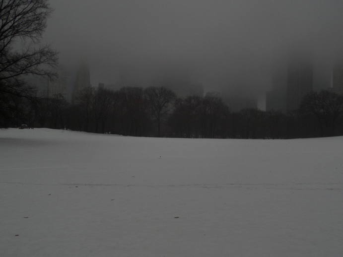 foggy buildings across a snowy field. a tiny red flag in the middle.