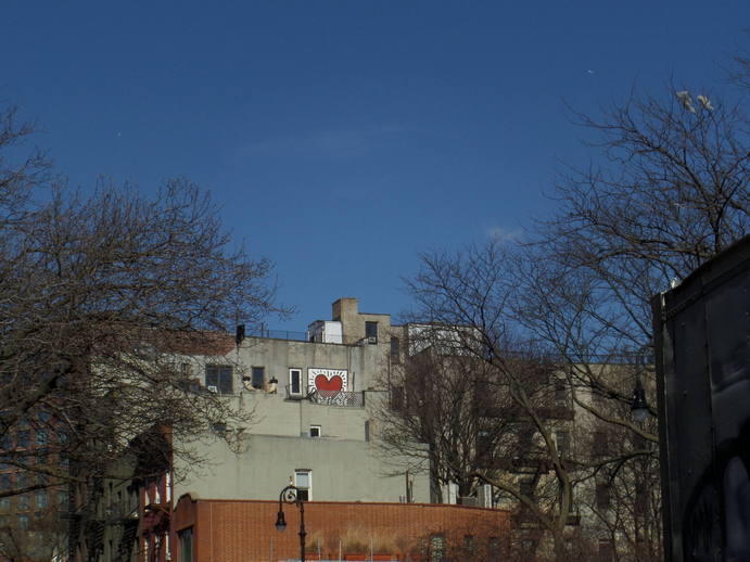 keith haring mural with a heart on a high building in the distance.