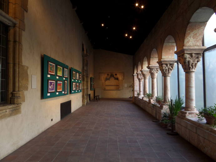 interior with muted natural light, archways to the right and children's drawings on the left wall.