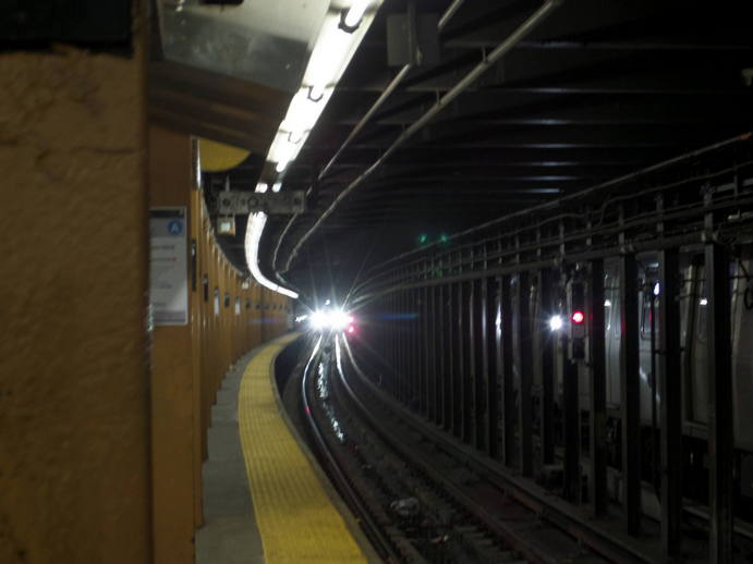 curved subway platform, train approaching.