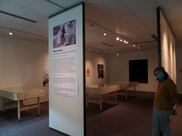 Queer ephemera in a gallery. View from the entrance. Titled 