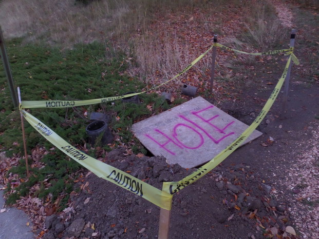 Caution tape surrounding a peice of plywood spraypainted to say 