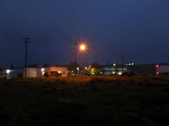 Blurry; an orange light making a star over a parking lot; nighttime