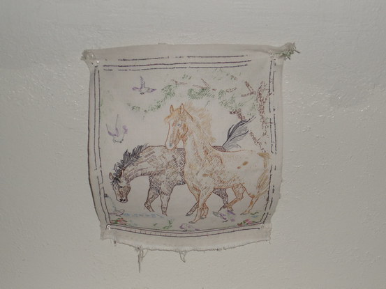 Flash photo of a white fabric decorated with two horses hanging from the ceiling.