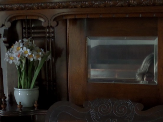 daffodils on an organ, half a face reflected in the mirror