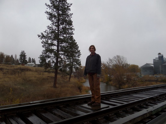 person stands on train bridge in the rain.